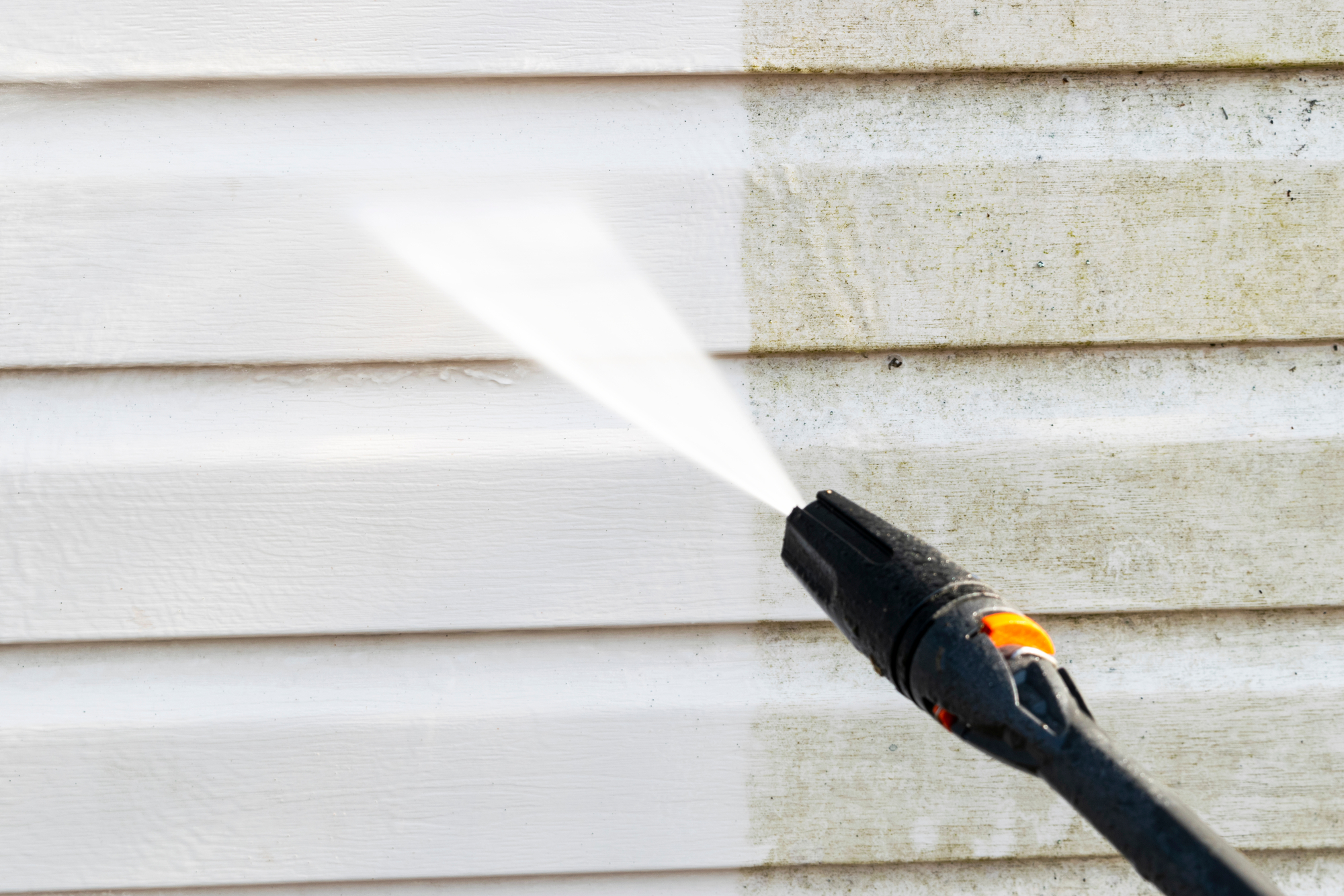 Cleaning service washing building facade with pressure water.